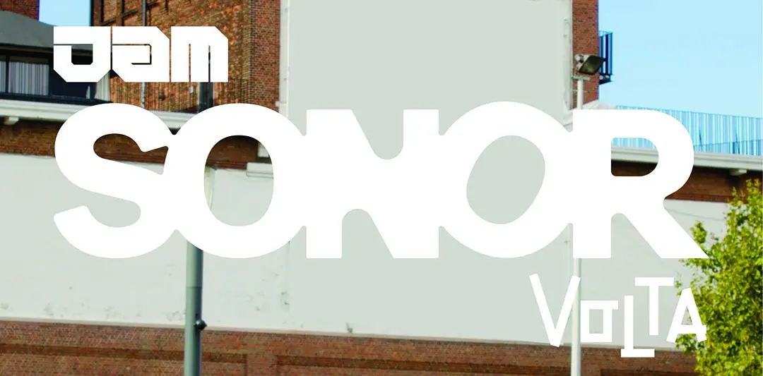 Dominant white typography overlay on an urban brick building backdrop; reads SOMOR with a smaller Volta in the lower right.